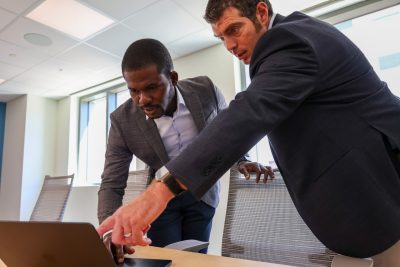 two people looking down at a computer