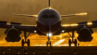 Airplane landing on runway at sunset
